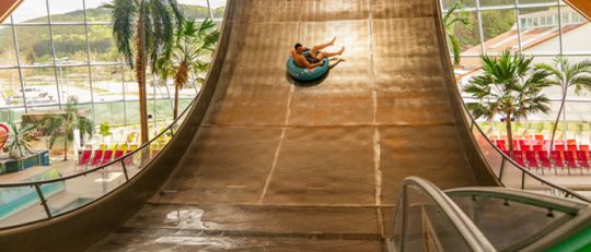 Person auf einem Reifen rutscht auf einer Wasserrutschen-Rampe