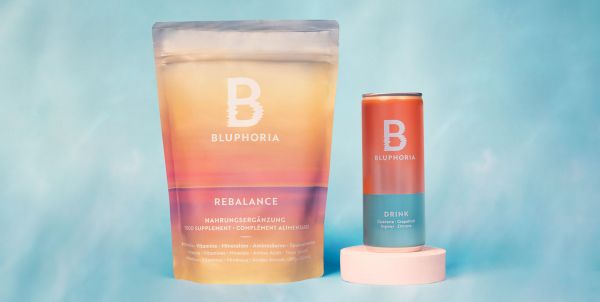 Bluphoria Rebalance Drink Set Die bunte Verpackung des Rebalance steht neben einer bunten Drink Dose vor blauem Hintergrund