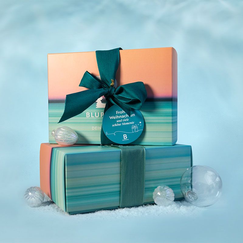 Bluphoria gift boxes In addition to Christmas baubles and artificial snow, two colourful, sanded boxes lie on top of each other