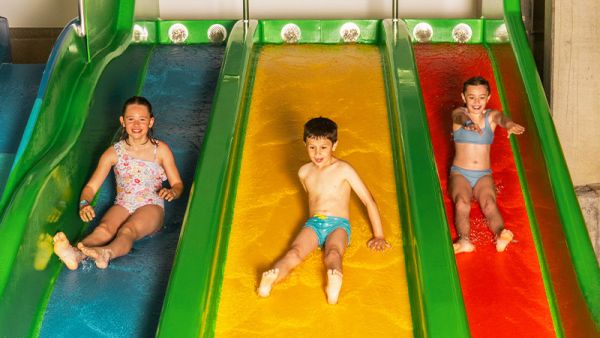 Drei Kinder auf einer Dreier-Rutsche rutschen gleichzeitig