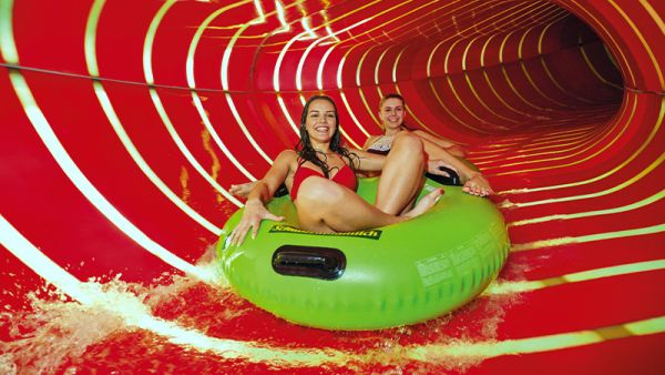 Zwei Frauen im Doppelreifen auf einer breiten Röhren-Wasserrutsche