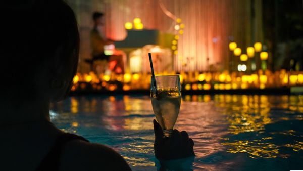 Siluette einer Person im Wasser mit Cocktail, Kerzenschein im Hintergrund