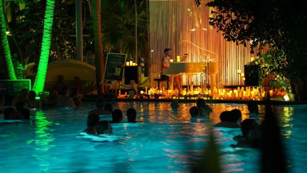 Siluette einer Person im Wasser mit Cocktail, Kerzenschein im Hintergrund