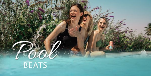 Drei Frauen sitzen am Pool und lachen