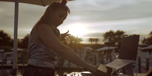 eine Frau steht am DJ Pult im Sonnenuntergang