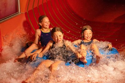 Drei Kinder rutschen lachend eine Reifenrutsche