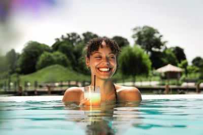 Eine Frau sitzt im Pool und lächelt