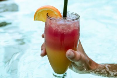 Bunter Cocktail in der Hand im Wasser