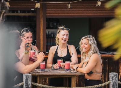 Eine Gruppe von Frauen steht lachend an einer Beachbar