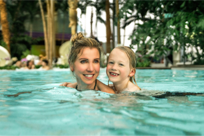 Eine Frau und ein Kind schwimmen in einer von Palmen umgebenen Wasserlandschaft