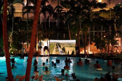 Kinofilm auf einer Leinwand, Menschen im Wasser unter Palmen