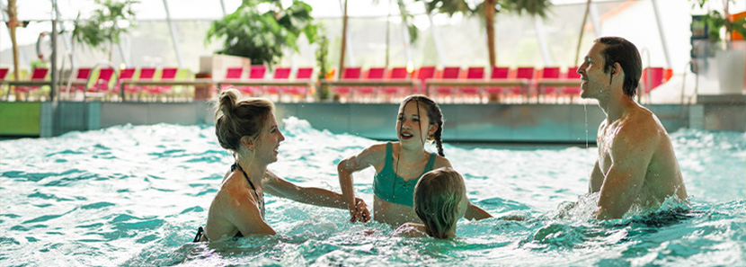 Familie tobt gemeinsam in großem Pool mit Wellenbad