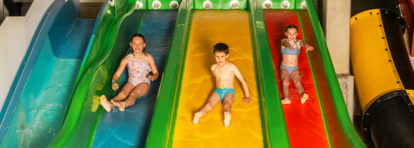 Triple-Slide Wasserrutsche im Galaxy Drei Kinder auf einer Dreier-Wasserrutsche rutschen nebeneinander